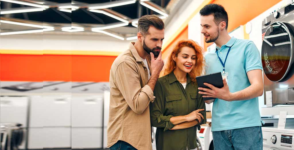 Customer service representative assisting a couple in a laundry store.