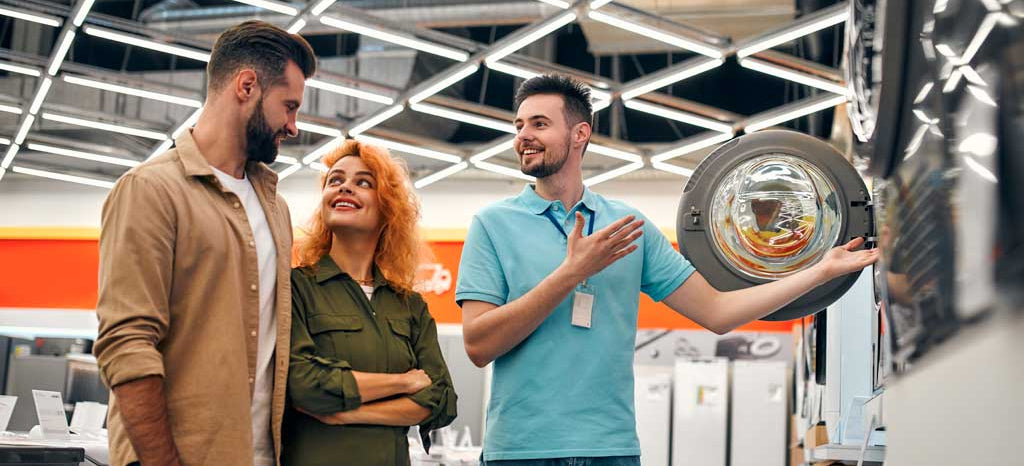 Customer service representative showing a product to two customers in a store.